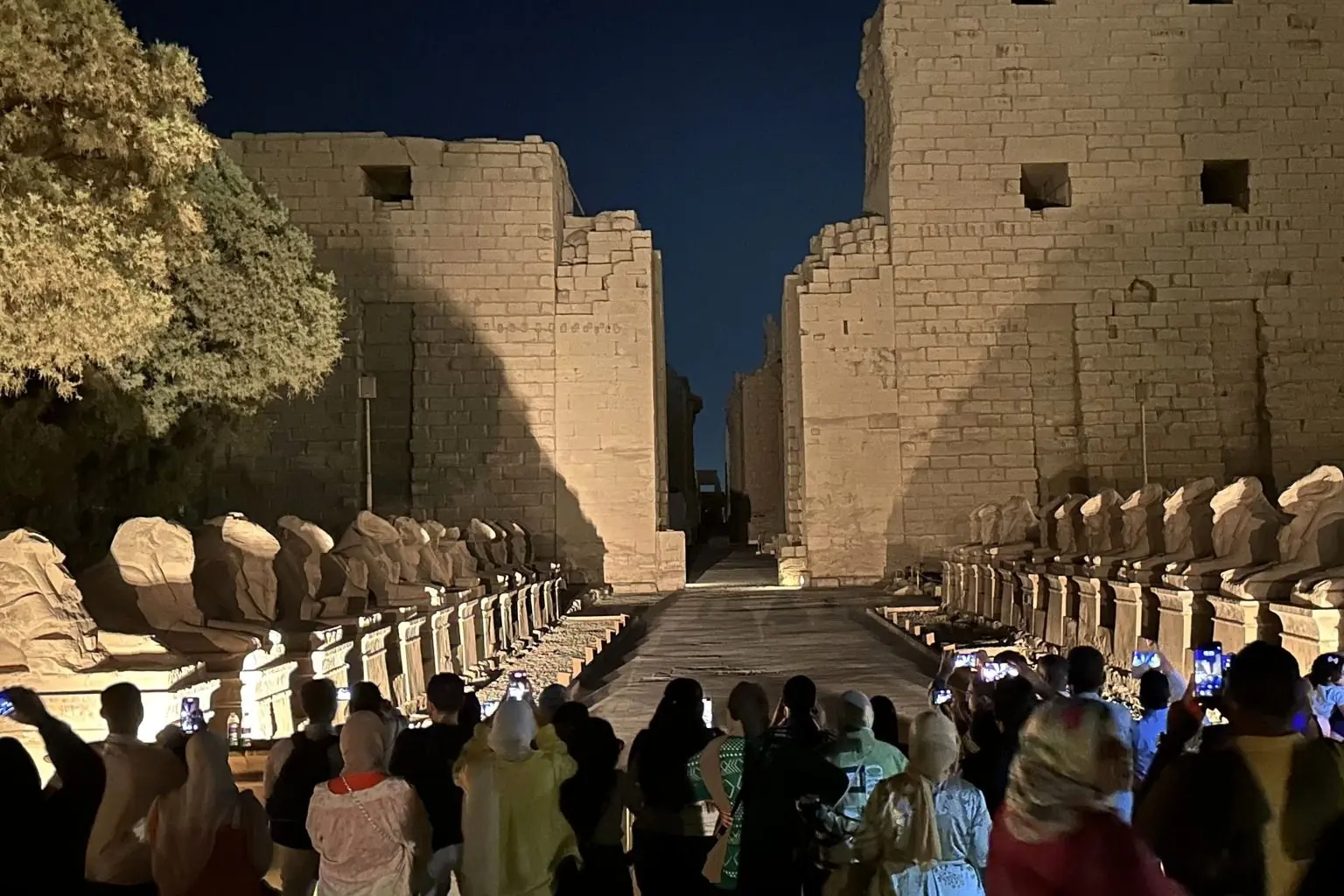 Visitors at the avenue of rams at the entrance to Karnak after dark