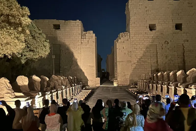 Visitors at the avenue of rams at the entrance to Karnak after dark