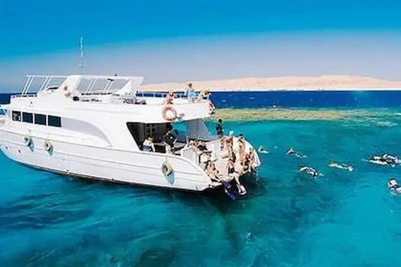 A day boat anchored at the reef with snorkelers in the water